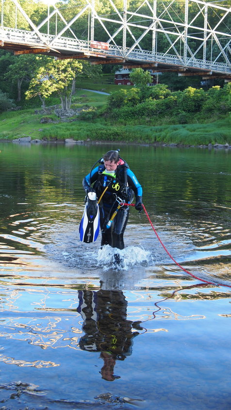 April White, a member of the Cochecton Ambulance Squad, backs into the river at the June 16  dive team drill at Skinner's Falls. She is tethered to a tender who directs her searching. A profiler will time and track her breathing and use of air supply. The tender uses are series of signals to guide the methodical search pattern, photo left.